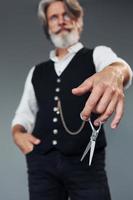 barbiere Strumenti. contro grigio sfondo. elegante moderno anziano uomo con grigio capelli e barba è in casa foto