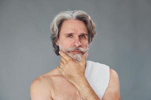 fresco e pulito viso. elegante moderno anziano uomo con grigio capelli e barba è in casa foto