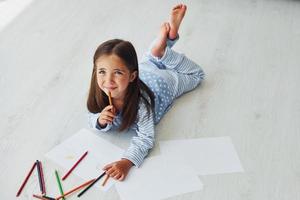 con matite e carta. creativo carino poco ragazza in casa a casa solo. bambino godendo fine settimana foto