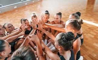 molti di le persone. gruppo di femmina bambini praticante atletico esercizi insieme in casa foto