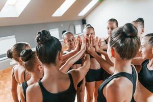 molti di le persone. gruppo di femmina bambini praticante atletico esercizi insieme in casa foto