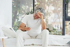 concezione di malattia e virus. anziano elegante moderno uomo con grigio capelli e barba in casa foto