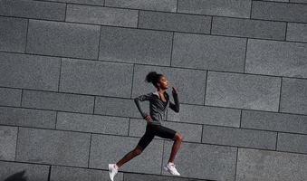attivo corridore. giovane africano americano donna nel allegro Abiti avere allenarsi all'aperto a giorno foto