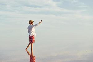 godendo maestoso Visualizza. uomo nel cappello e casuale Abiti passeggiate su lago a jarilgach isola, Ucraina foto