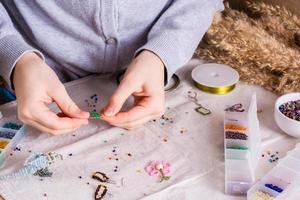 figli di mani tessere un' perline giocattolo su un' tavolo tra scatole con perline. figli di tempo libero foto