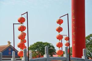 tutti e due di Cinese rosso lanterna ha scritto fortunato e Cinese modello, decorazione sospeso vicino un' rosso grande pilastro scritto oro Cinese personaggi. foto