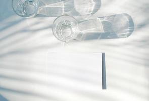 vuoto attività commerciale carta modello su bicchiere con ombra di naturale le foglie ombra copertura su bianca sfondo, per Prodotto o presentazione foto