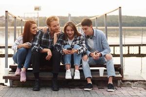 vicino il lago. gruppo di giovane allegro amici quello è all'aperto avendo divertimento insieme foto