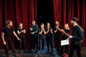 uomo è praticante il suo ruolo. gruppo di attori nel buio colorato Abiti su prova nel il Teatro foto