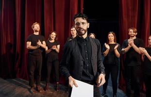 uomo è praticante il suo ruolo. gruppo di attori nel buio colorato Abiti su prova nel il Teatro foto