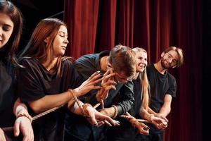 nodo nel il mani. gruppo di attori nel buio colorato Abiti su prova nel il Teatro foto