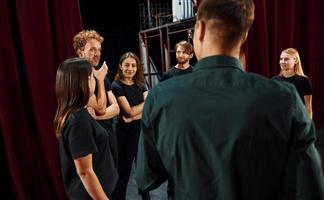 Lavorando insieme. gruppo di attori nel buio colorato Abiti su prova nel il Teatro foto