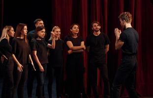 gruppo di attori nel buio colorato Abiti su prova nel il Teatro foto