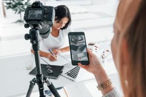 fotografo a opera. Due giovane femmina liberi professionisti in casa nel il ufficio a giorno foto