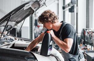 mutevole olio. adulto uomo nel grigio colorato uniforme lavori nel il automobile salone foto