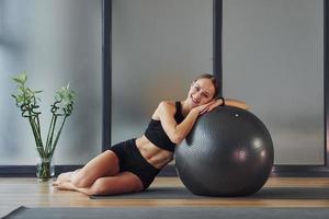 assunzione un' rompere. giovane donna nel allegro indossare e con sottile corpo avere fitness yoga giorno in casa foto