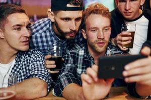 usi Telefono. gruppo di persone insieme in casa nel il pub avere divertimento a fine settimana tempo foto