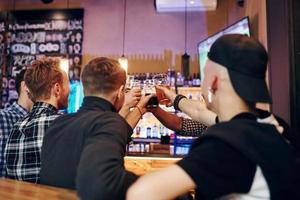 applauso di colpi birra occhiali. gruppo di persone insieme in casa nel il pub avere divertimento a fine settimana tempo foto