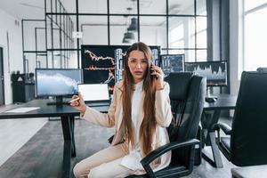 parla di Telefono. giovane femmina azione broker lavori in casa nel il ufficio. molti di viene visualizzato foto