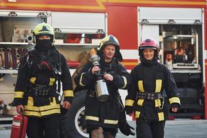 gruppo di i vigili del fuoco nel protettivo uniforme quello all'aperto vicino camion foto