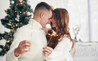 con sparklers nel mani. giovane romantico coppia celebra nuovo anno insieme in casa foto