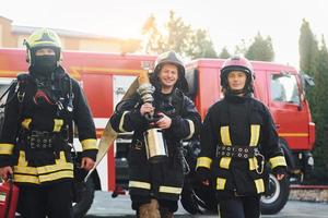 gruppo di i vigili del fuoco nel protettivo uniforme quello all'aperto vicino camion foto