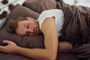 uomo dorme su il letto. interno e design di bellissimo moderno Camera da letto a giorno foto