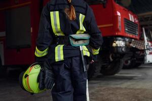 vicino su Visualizza. femmina pompiere nel protettivo uniforme in piedi vicino camion foto