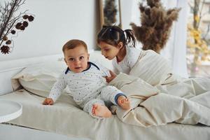 Due bambini avere divertimento mentre mentendo giù su letto. interno e design di bellissimo moderno Camera da letto a giorno foto