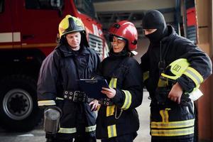 con bloc notes. gruppo di i vigili del fuoco nel protettivo uniforme quello è su stazione foto