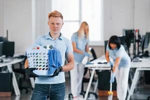 uomo detiene cestino. gruppo di lavoratori pulito moderno ufficio insieme a giorno foto