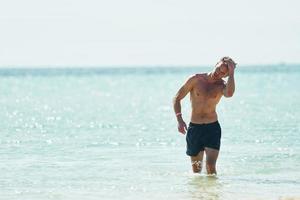 chiaro acqua. giovane europeo uomo avere vacanza e godendo gratuito tempo su il spiaggia di mare foto