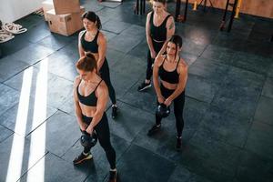 sollevamento di pesante pesi. gruppo di giovane allegro persone avere CrossFit giorno in casa nel Palestra foto