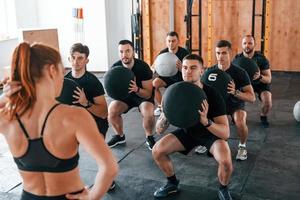 con fitness palle. gruppo di giovane allegro persone avere CrossFit giorno in casa nel Palestra foto