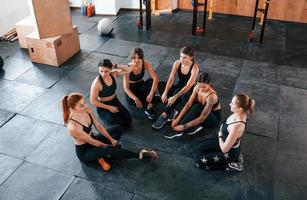 seduta su pavimento. gruppo di giovane allegro persone avere CrossFit giorno in casa nel Palestra foto