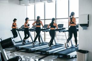 in esecuzione su un' tapis roulant. gruppo di giovane allegro persone avere CrossFit giorno in casa nel Palestra foto