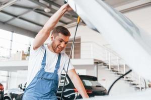 giovane uomo nel bianca camicia e blu uniforme riparazione automobile foto