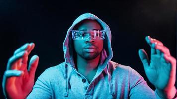 nel speciale occhiali. futuristico neon illuminazione. giovane africano americano uomo nel il studio foto