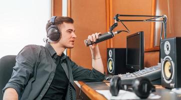 parla e usi microfono. giovane uomo è in casa nel il Radio studio è occupato di trasmissione foto