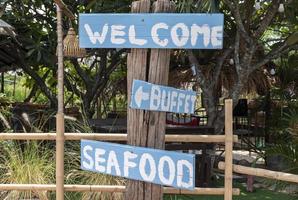 blu di legno cartello con un' Messaggio benvenuto ,buffet e frutti di mare foto