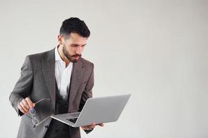 con il computer portatile nel mani. giovane elegante uomo d'affari nel completo da uomo al chiuso. concezione di successo foto