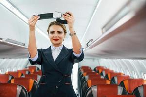 sicurezza Istruzioni. giovane hostess su il opera nel il passanger aereo foto