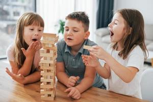 focalizzata su il confusione Torre gioco. bambini avendo divertimento nel il domestico camera a giorno insieme foto