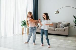 danza insieme. bambini avendo divertimento nel il domestico camera a giorno foto