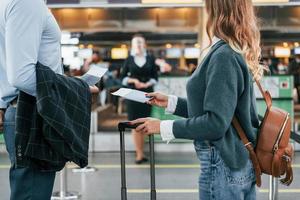 guardare a il dipendente. giovane coppia è nel il aeroporto insieme foto