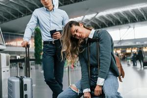 donna è stanco. giovane coppia è nel il aeroporto insieme foto