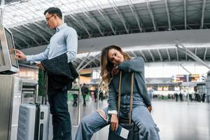 donna è stanco. giovane coppia è nel il aeroporto insieme foto