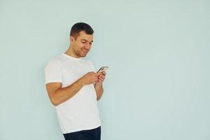 uomo nel casuale Abiti in piedi nel il studio con Telefono nel mani foto