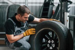 sostituzione di il vecchio pneumatico. uomo nel uniforme è Lavorando nel il auto servizio foto