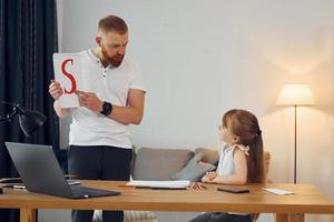 apprendimento lettere. padre con il suo poco figlia è a casa insieme foto